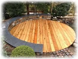 Runde Holzterrasse mit geschwungener Steineinfassung.