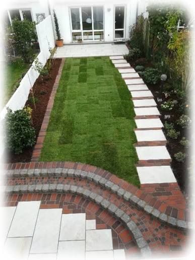 Ein Hinterhof mit einer gestuften Ziegelterrasse, Rasen und einem Steinweg, der zu einer weißen Tür führt.