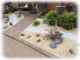 Zen-Garten mit Steinweg, kleinen Pflanzen, Kies und Büschen.