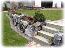 Ein hohes, graues Metallschiebetor entlang einer Grundstücksgrenze schützt eine Einfahrt; im Hintergrund sind ein Baum und ein Haus zu sehen.