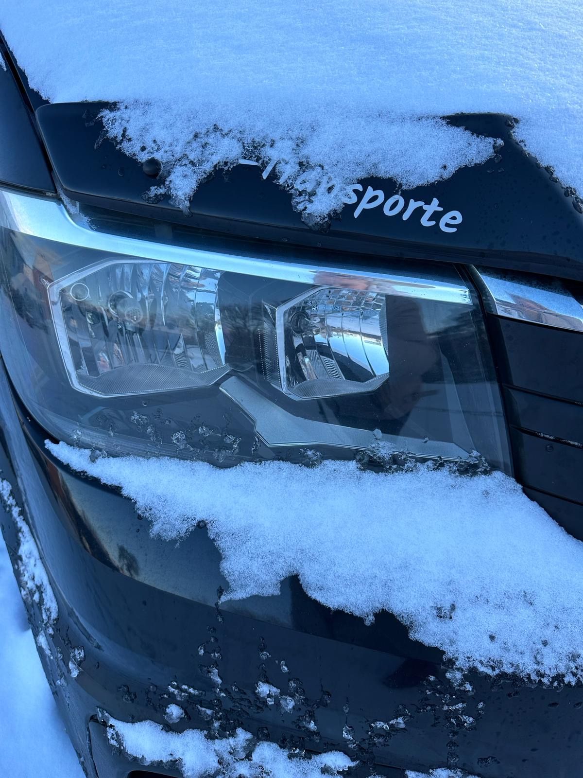 Eine Nahaufnahme eines schneebedeckten Autoscheinwerfers.