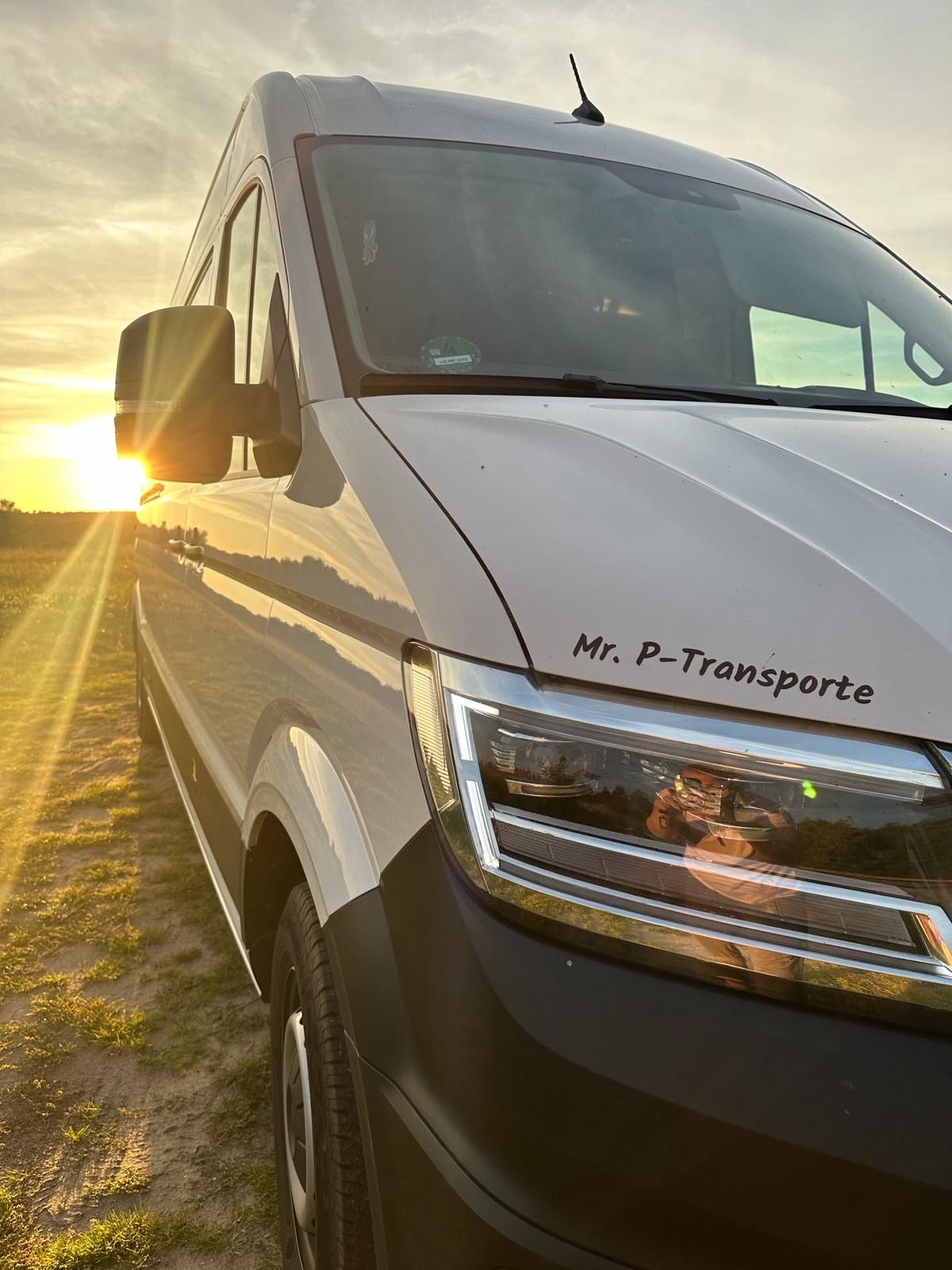 Ein weißer Lieferwagen parkt bei Sonnenuntergang auf einem Feld.