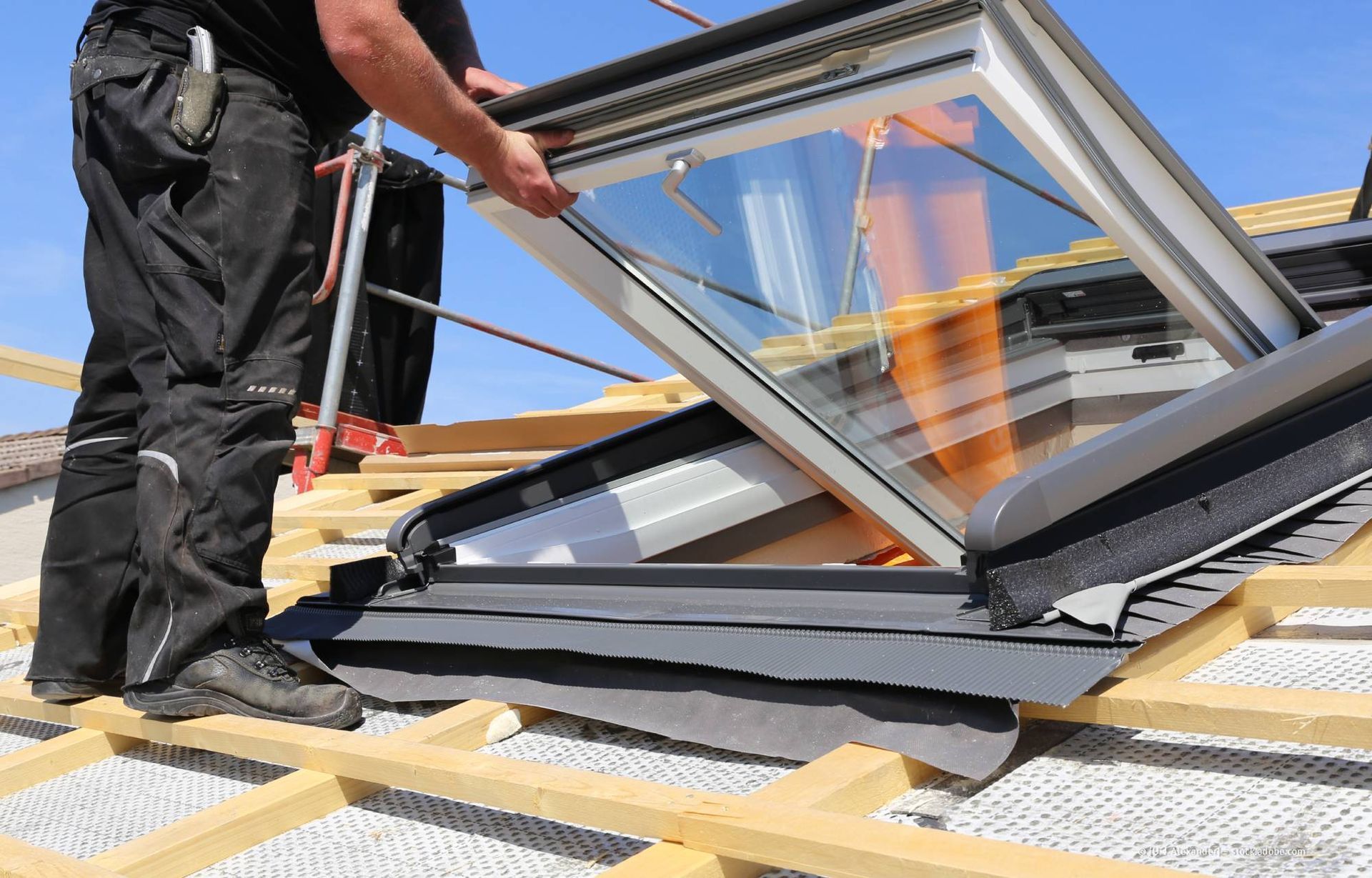 Gebäude mit roten Ziegeldächern und kleinen Dachgauben, blaue und gelbe Fassaden vor blauem Himmel.