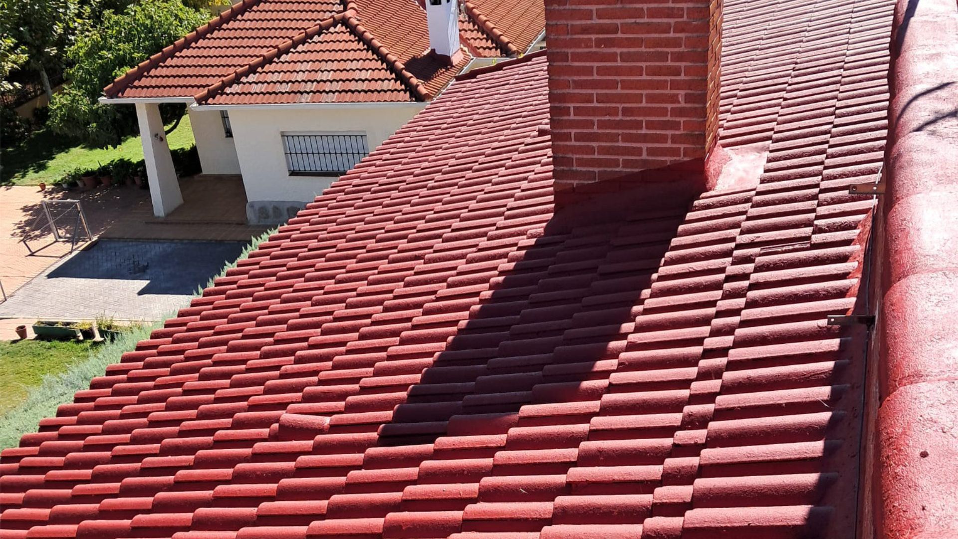 Un techo de tejas rojas con una chimenea encima.