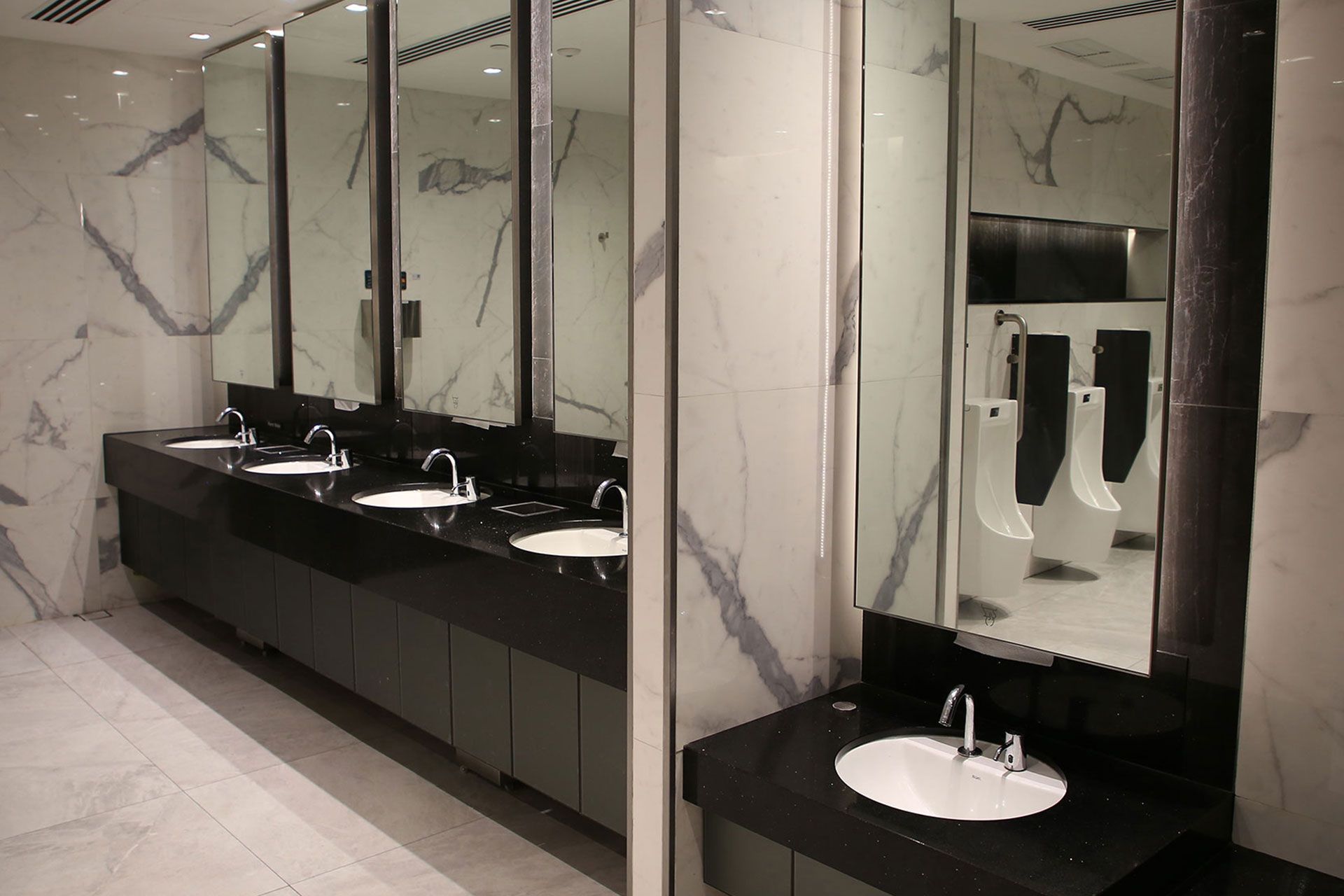 Moderne elegante öffentliche Toilette mit Waschbecken und Pissoirs