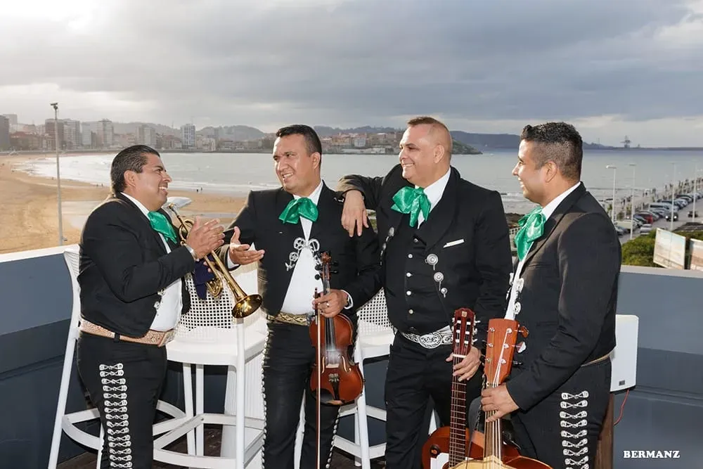 Cuatro músicos de mariachi, vestidos con trajes negros y corbatas verdes