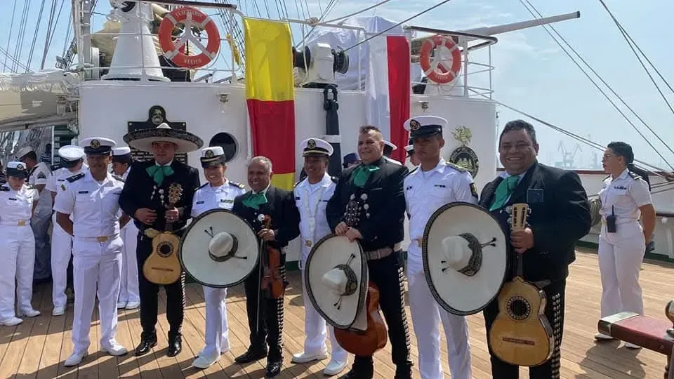 Músicos con uniformes blancos y sombreros negros posan en la cubierta de un barco