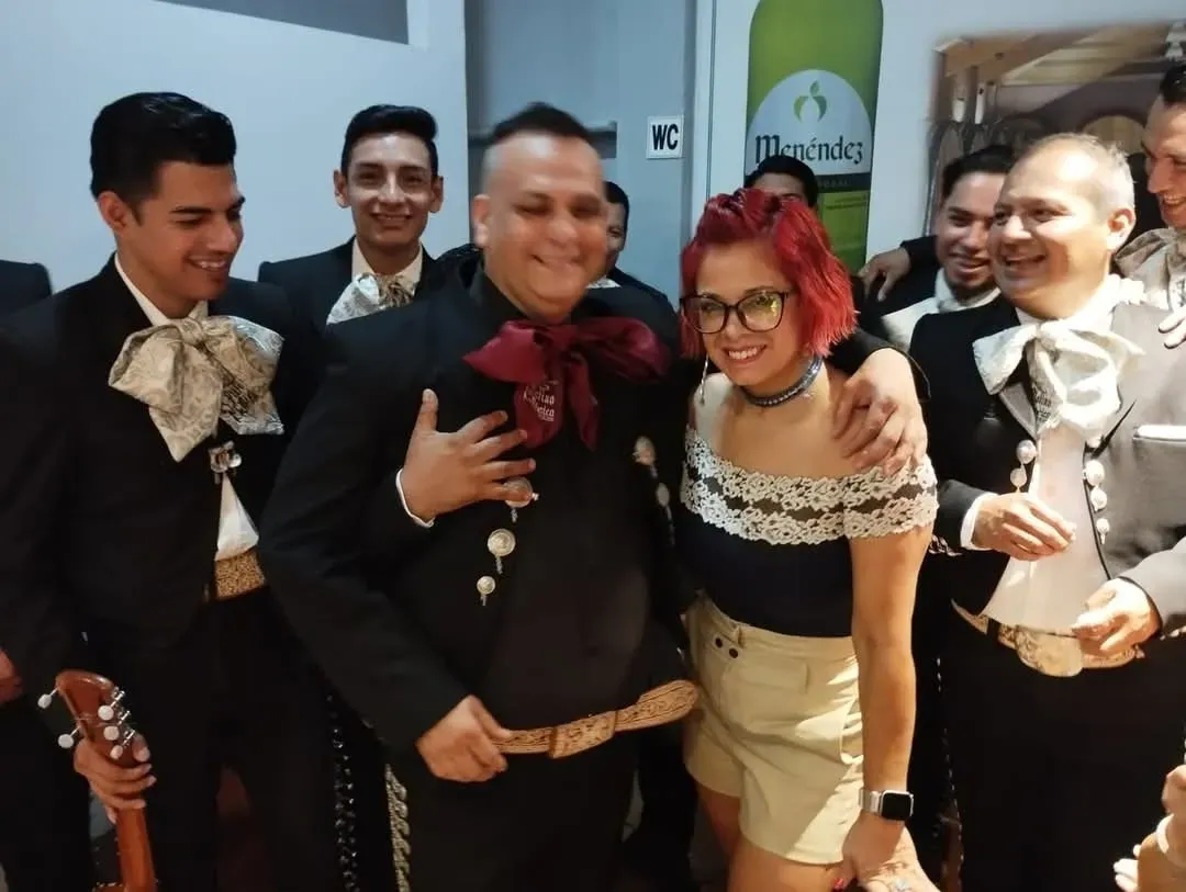Grupo de artistas con trajes en blanco y negro, posando en interiores y sonriendo con sus instrumentos.
