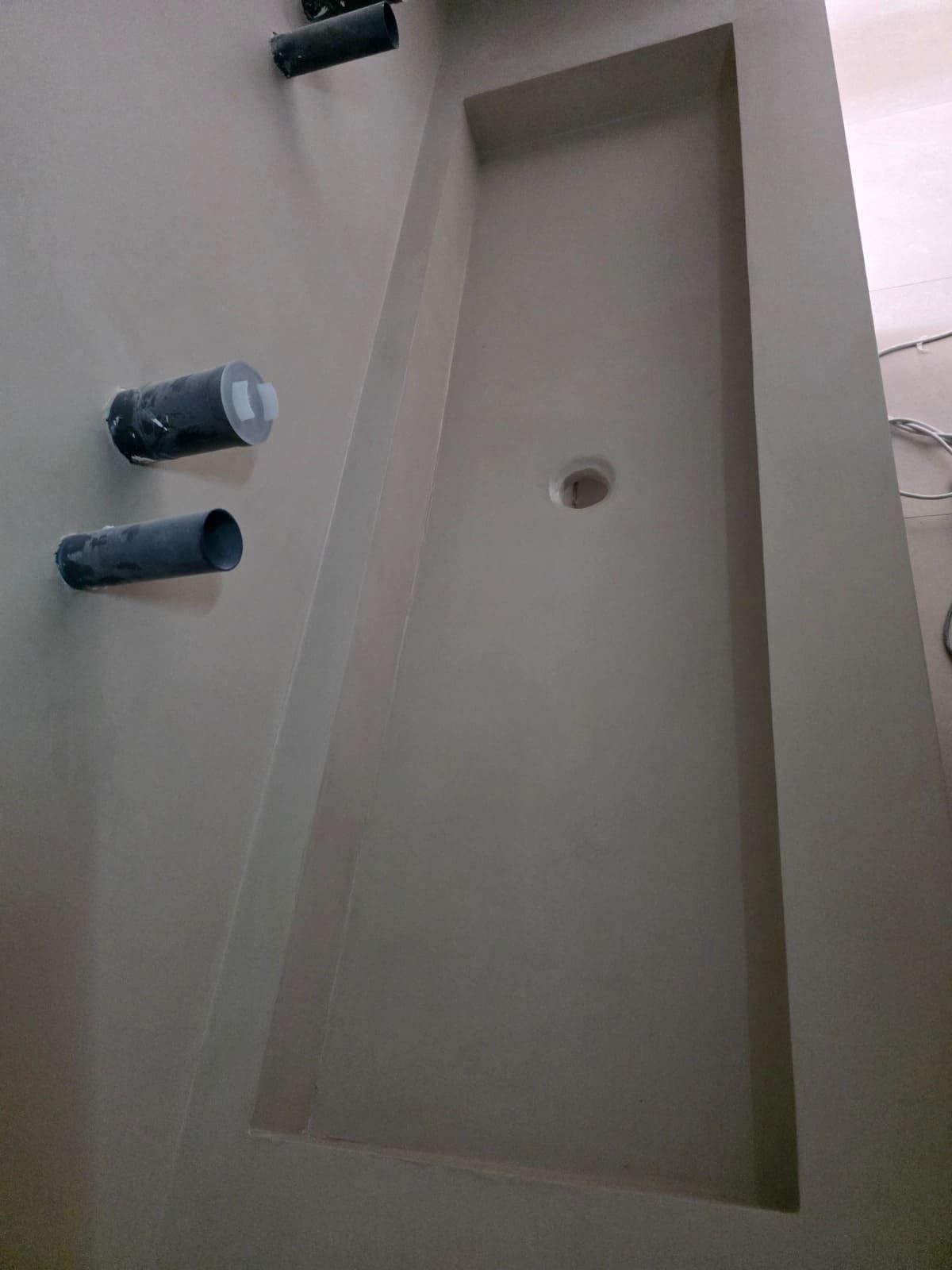 Lavabo de baño color beige con dos grifos oscuros instalados en el lado izquierdo.