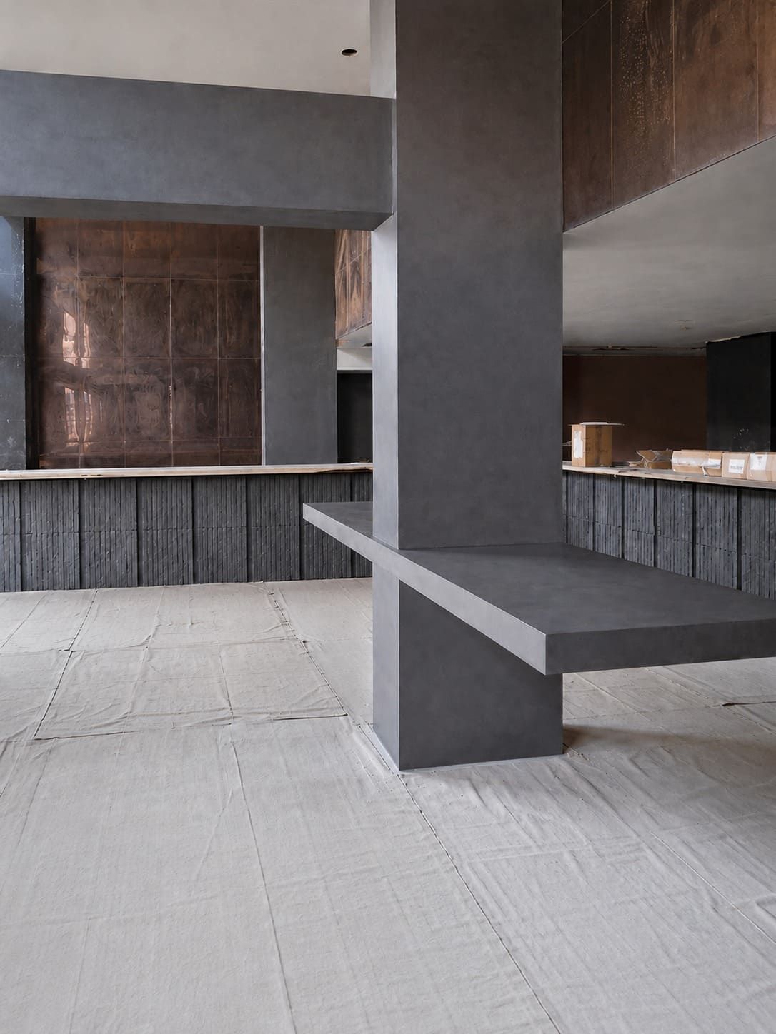 Interior moderno y vacío con columnas grises, suelo blanco y encimeras de madera oscura y piedra.