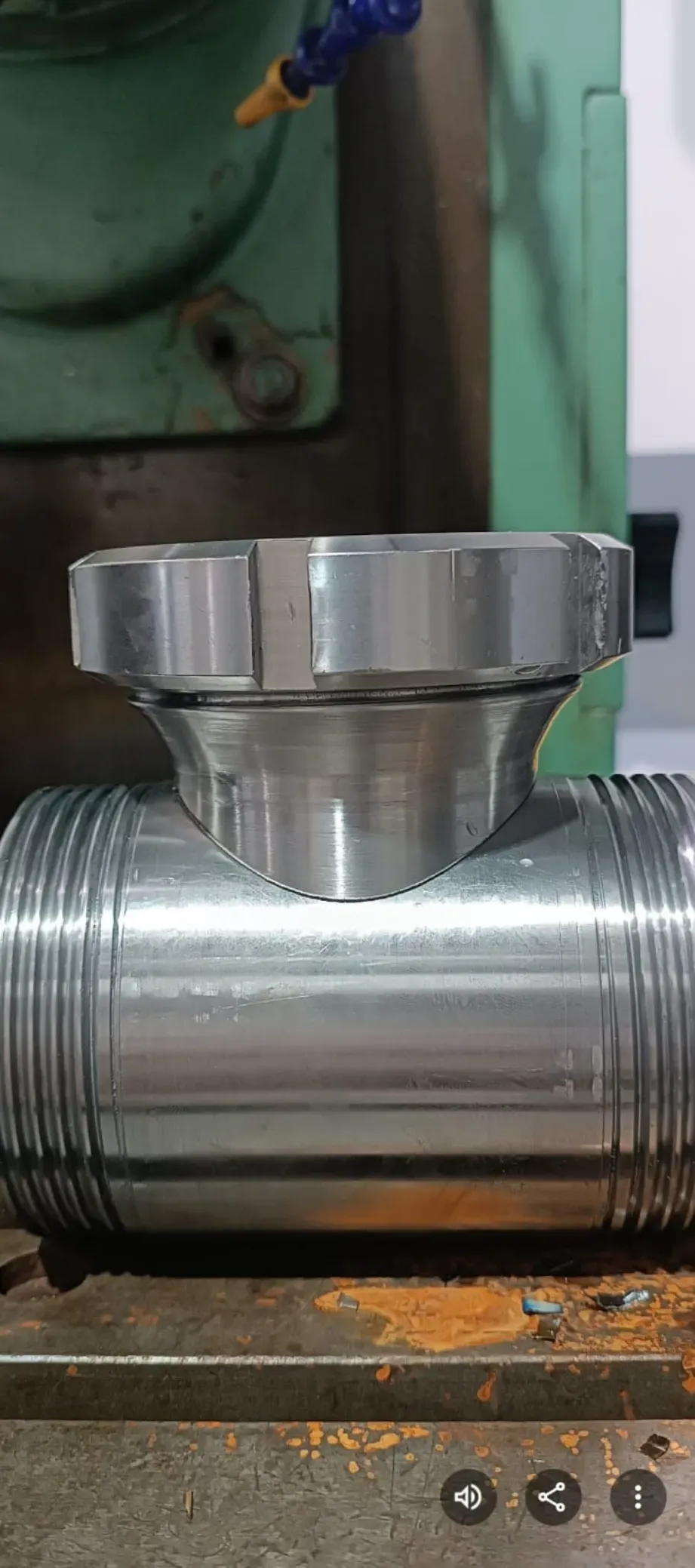 Conexión de válvula metálica montada en un tubo plateado roscado en un entorno industrial.