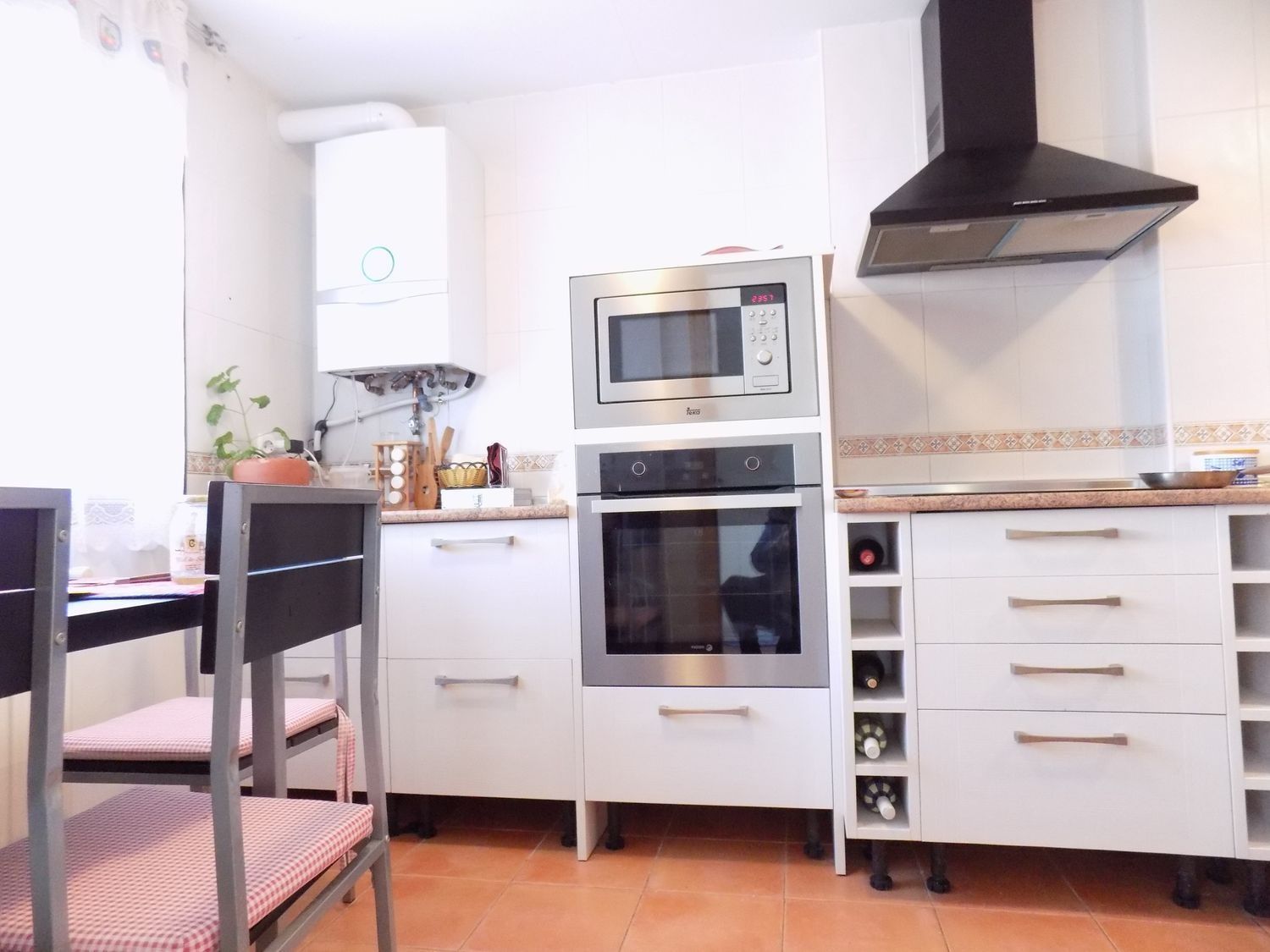 Una cocina con gabinetes blancos y electrodomésticos de acero inoxidable.