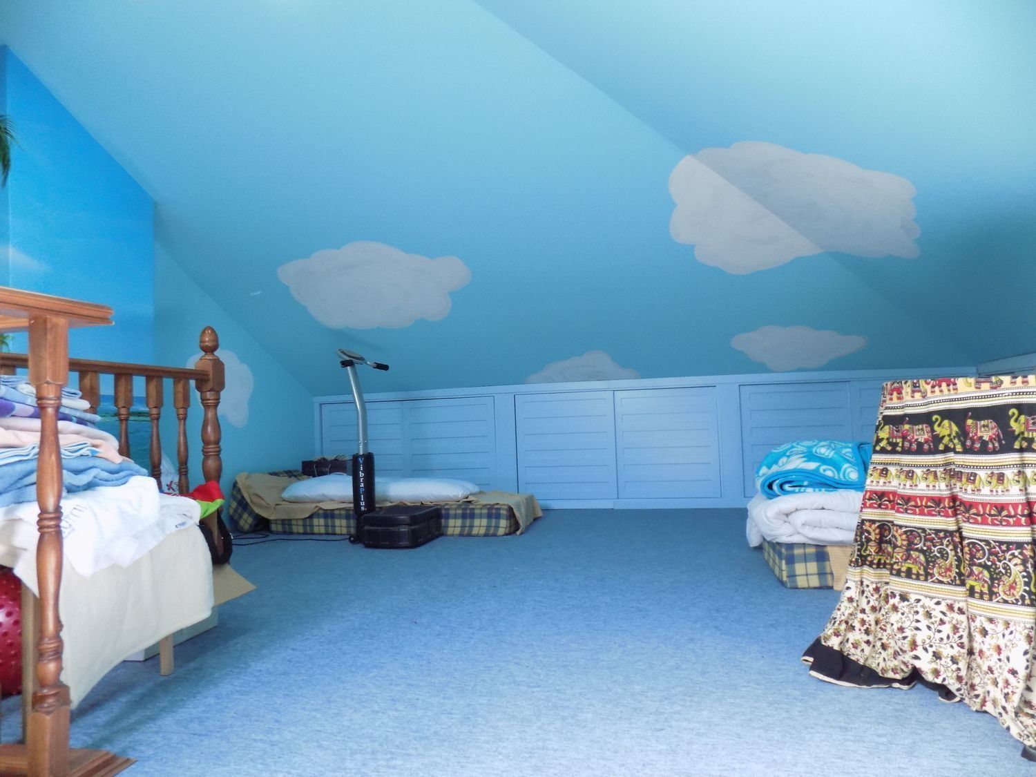 Un dormitorio con paredes azules y nubes blancas en el techo.