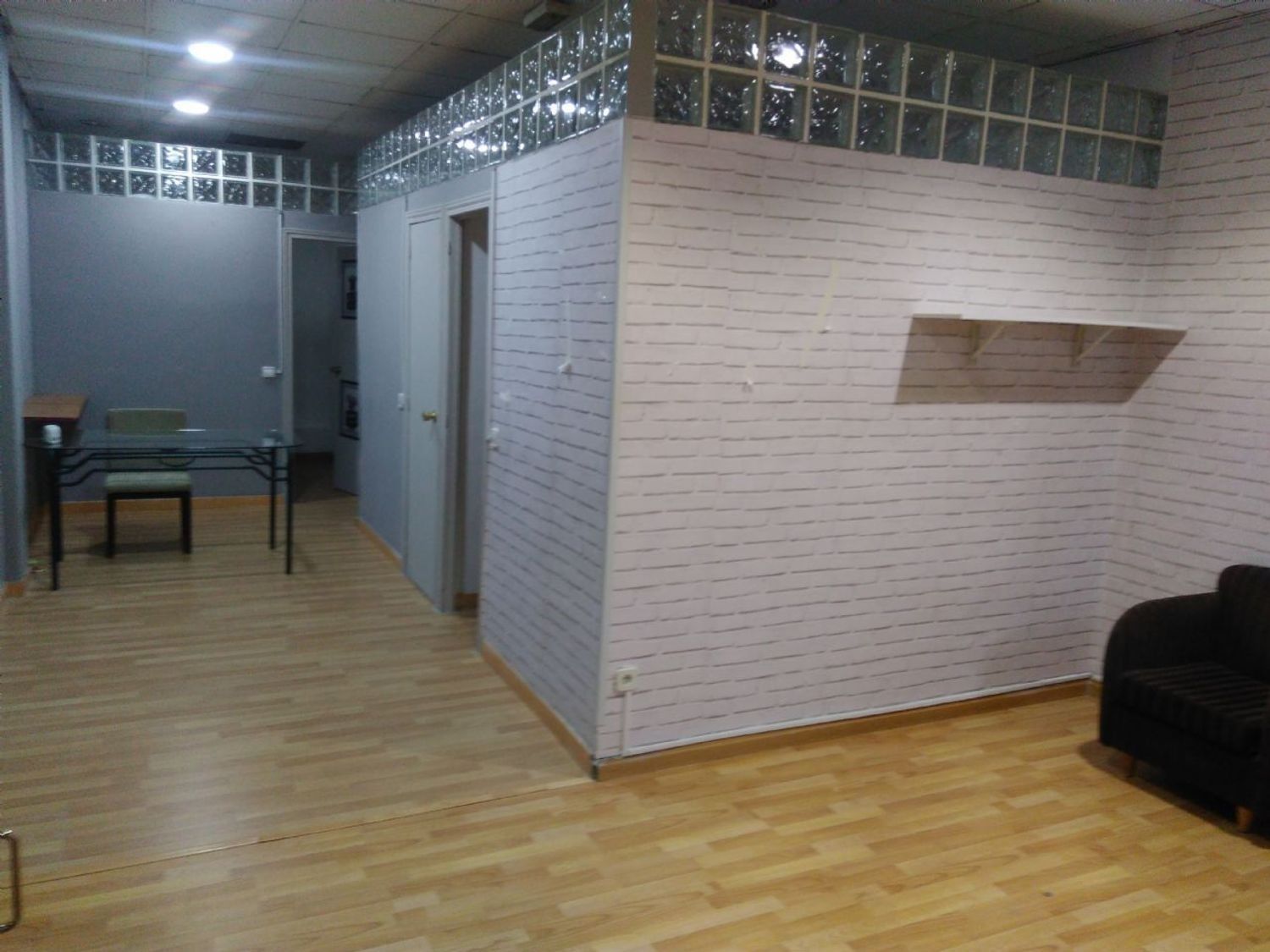 Una sala de estar con pisos de madera y una mesa y sillas de vidrio.
