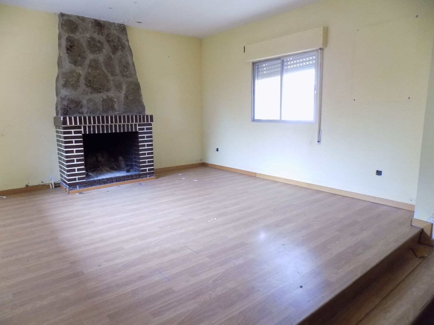 Una sala de estar vacía con chimenea y una ventana.