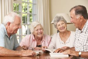 Vier Senioren sitzen am Tisch und lächeln