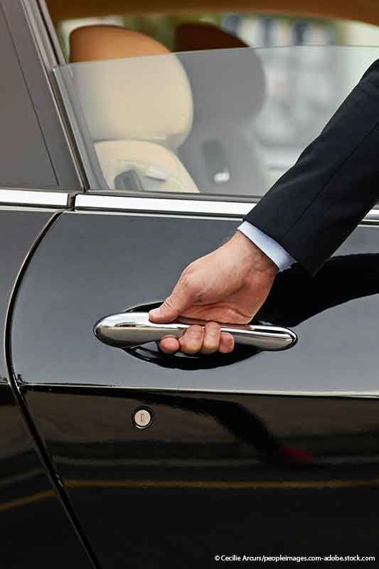 Hand öffnet eine schwarze Autotür.