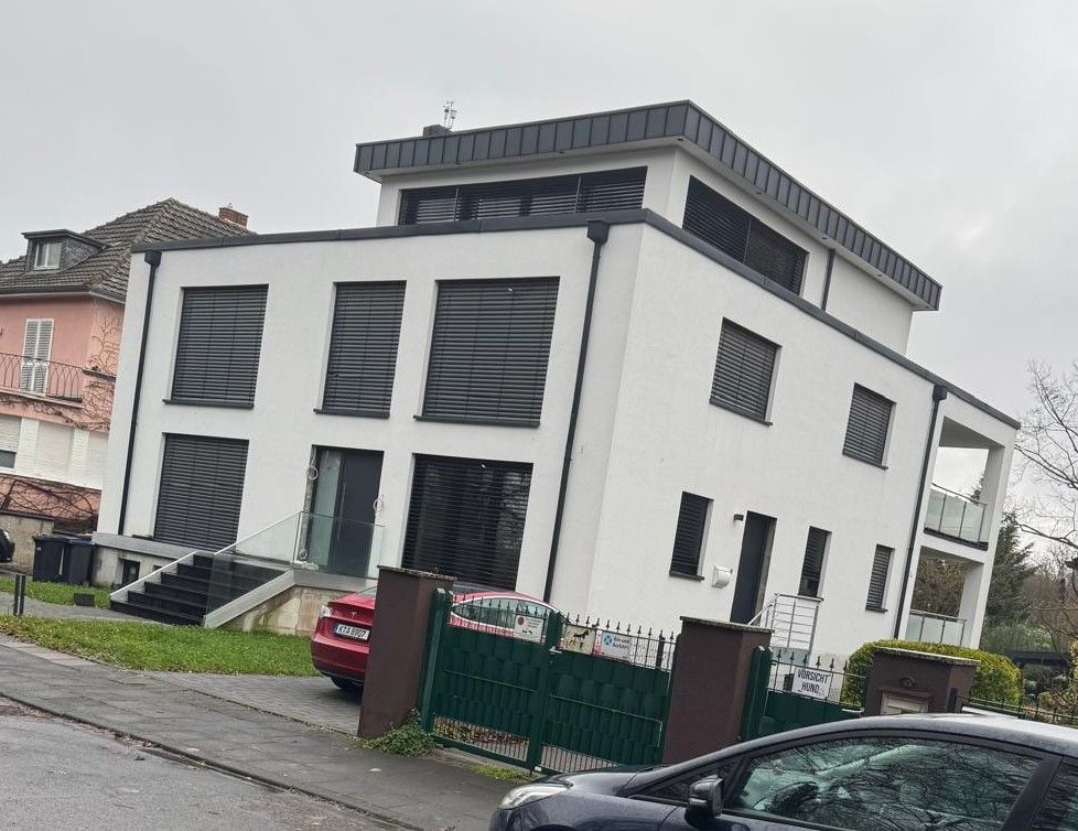 Vor einem großen weißen Gebäude parkt ein Auto.