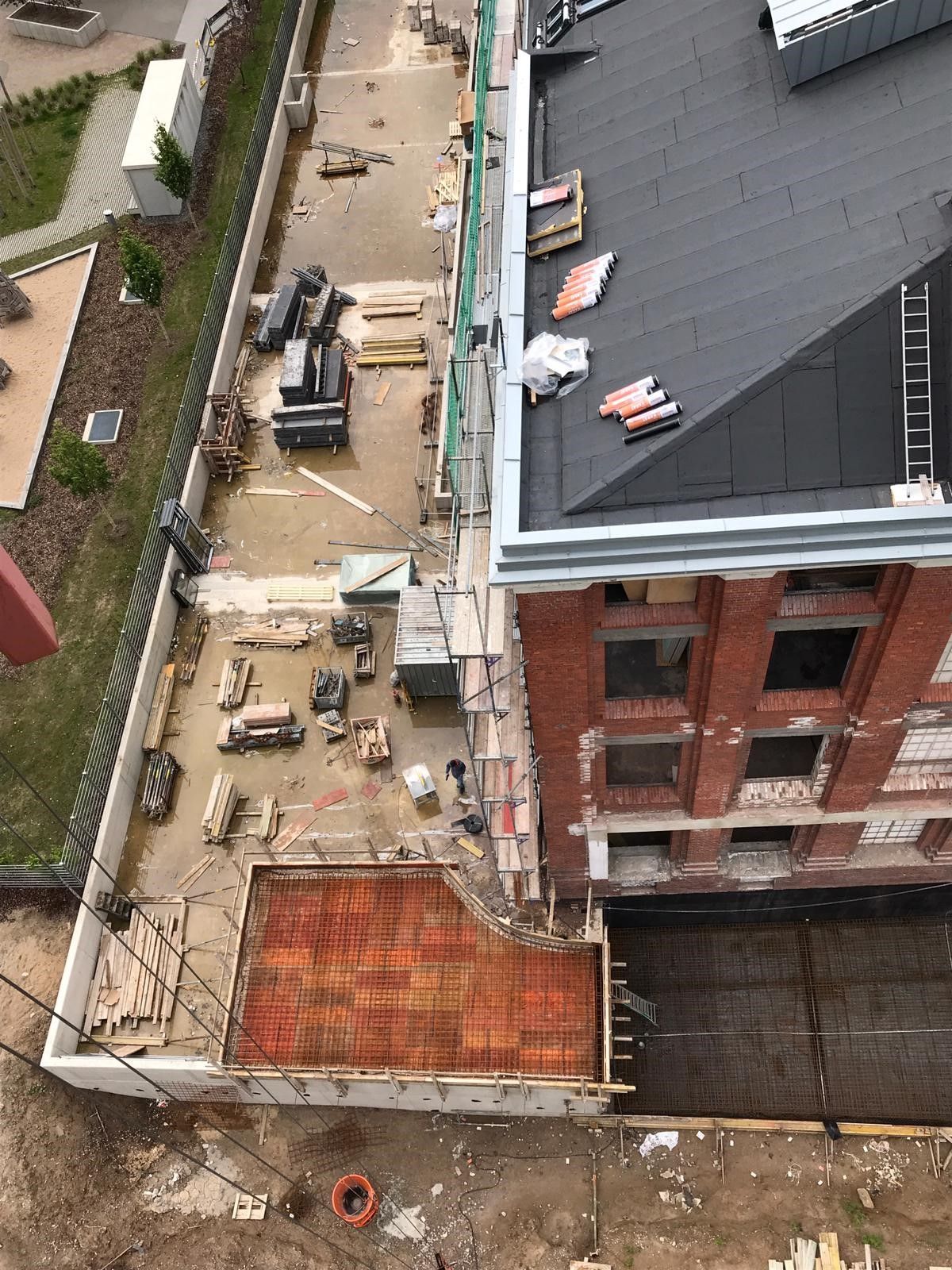 Eine Luftaufnahme einer Baustelle mit einem Backsteingebäude im Hintergrund.