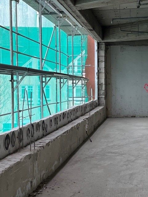 Ein leerer Raum mit einem großen Fenster und einem Gerüst an der Wand.