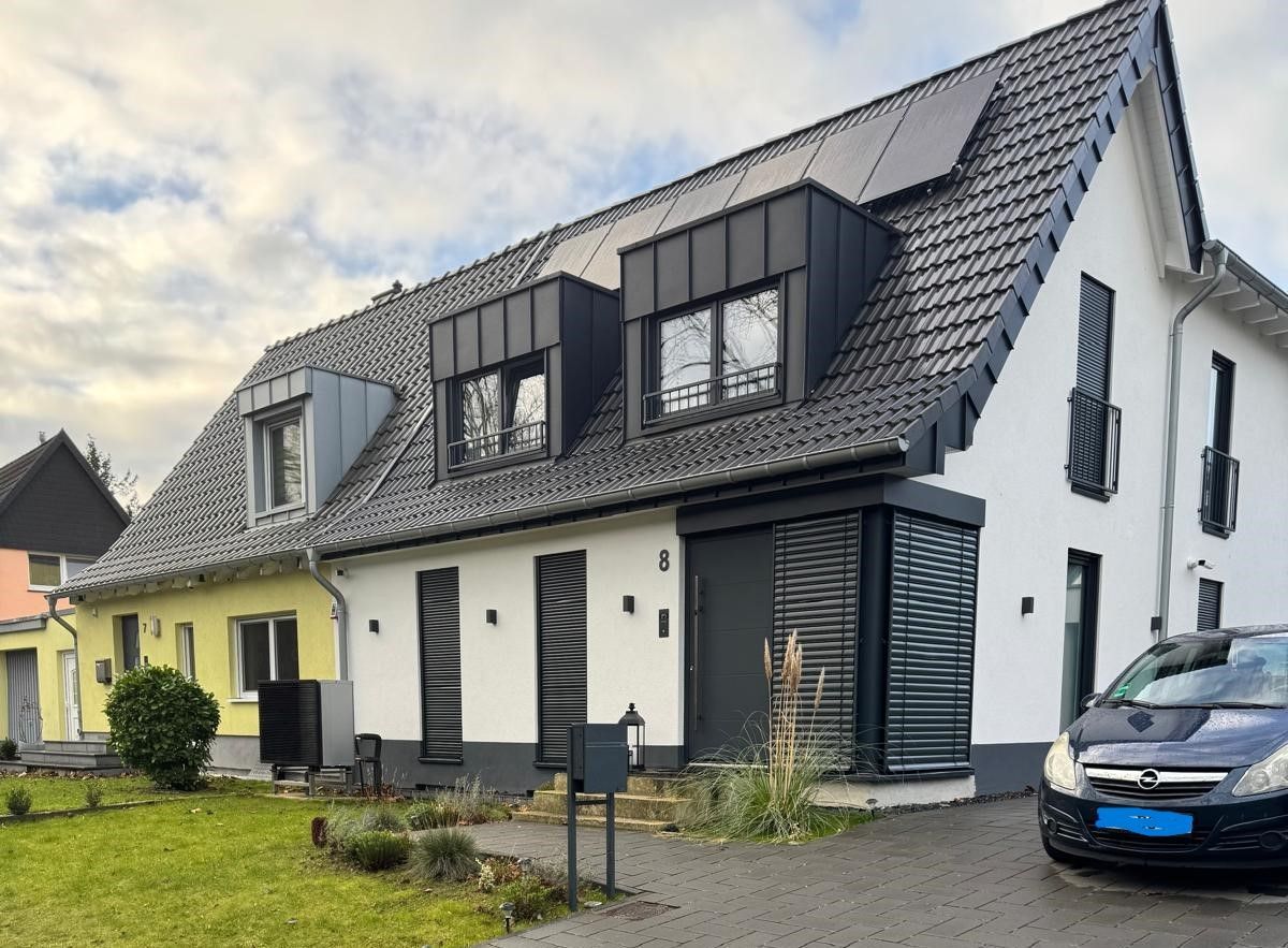 Vor einem weißen Haus parkt ein Auto.