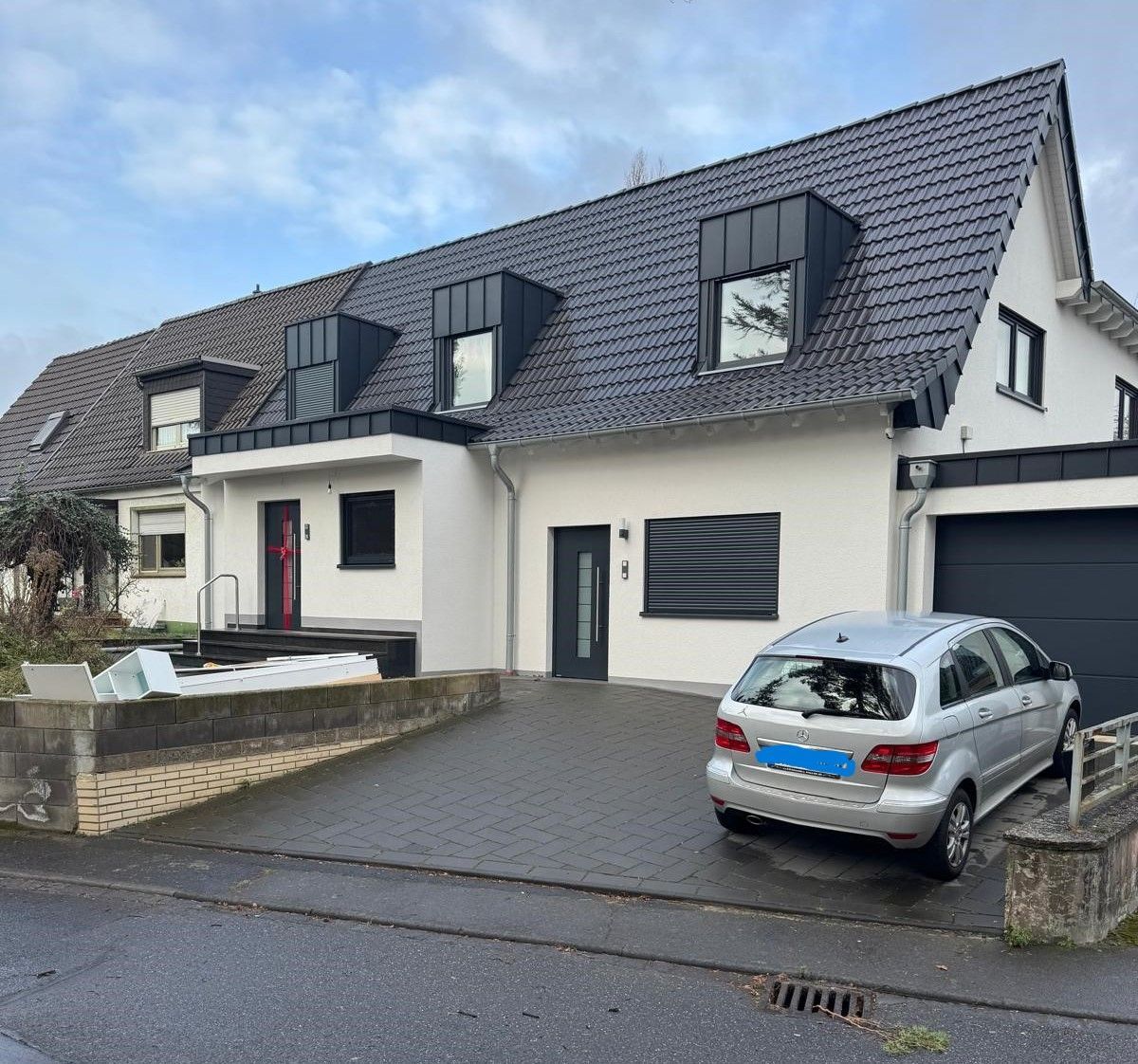 Ein Auto parkt vor einem weißen Haus