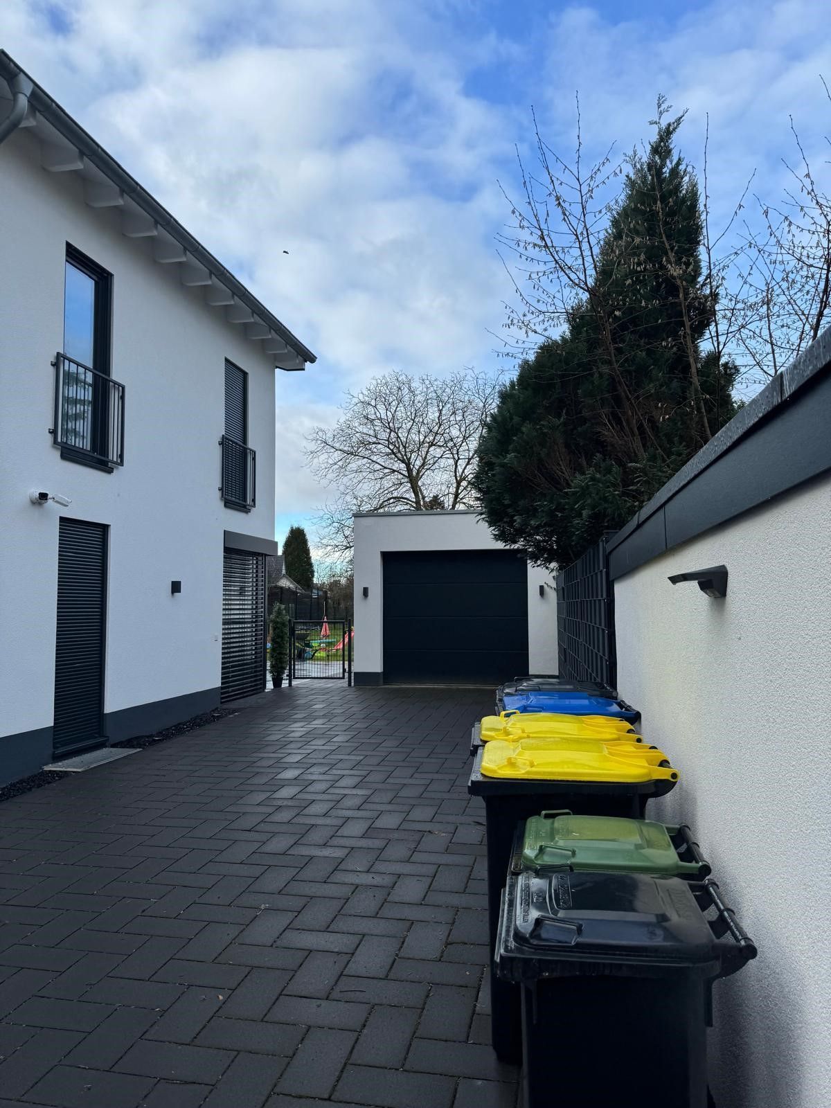 Eine Reihe von Mülltonnen vor einem weißen Haus