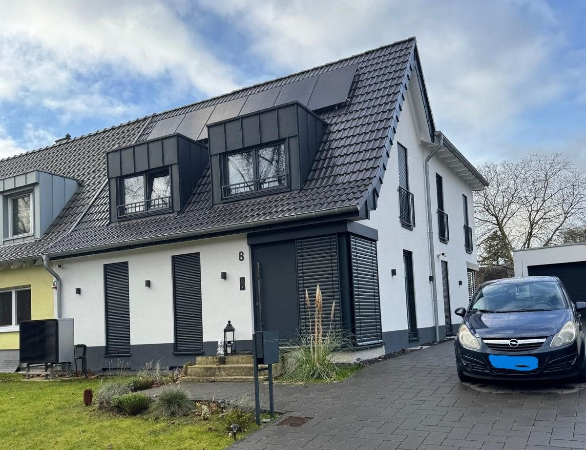 Ein schwarzes Auto parkt vor einem weißen Haus.