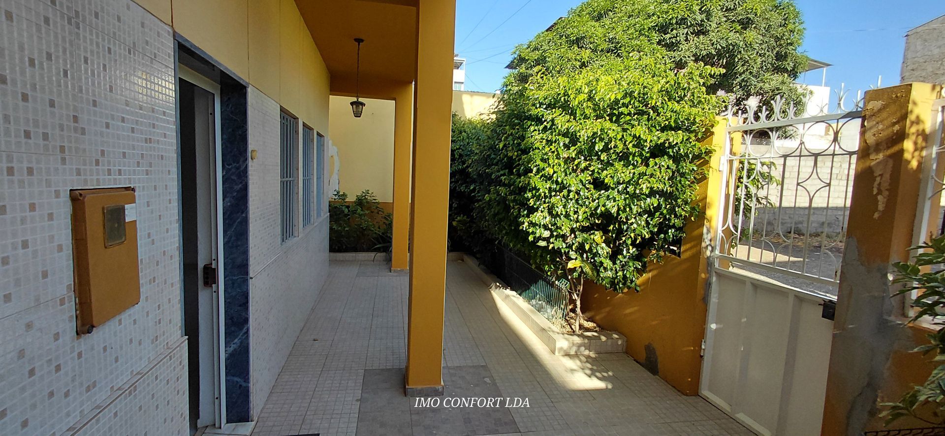 Cozinha moderna com armários brancos, detalhes em azul e uma ilha central com dois bancos altos de arame.