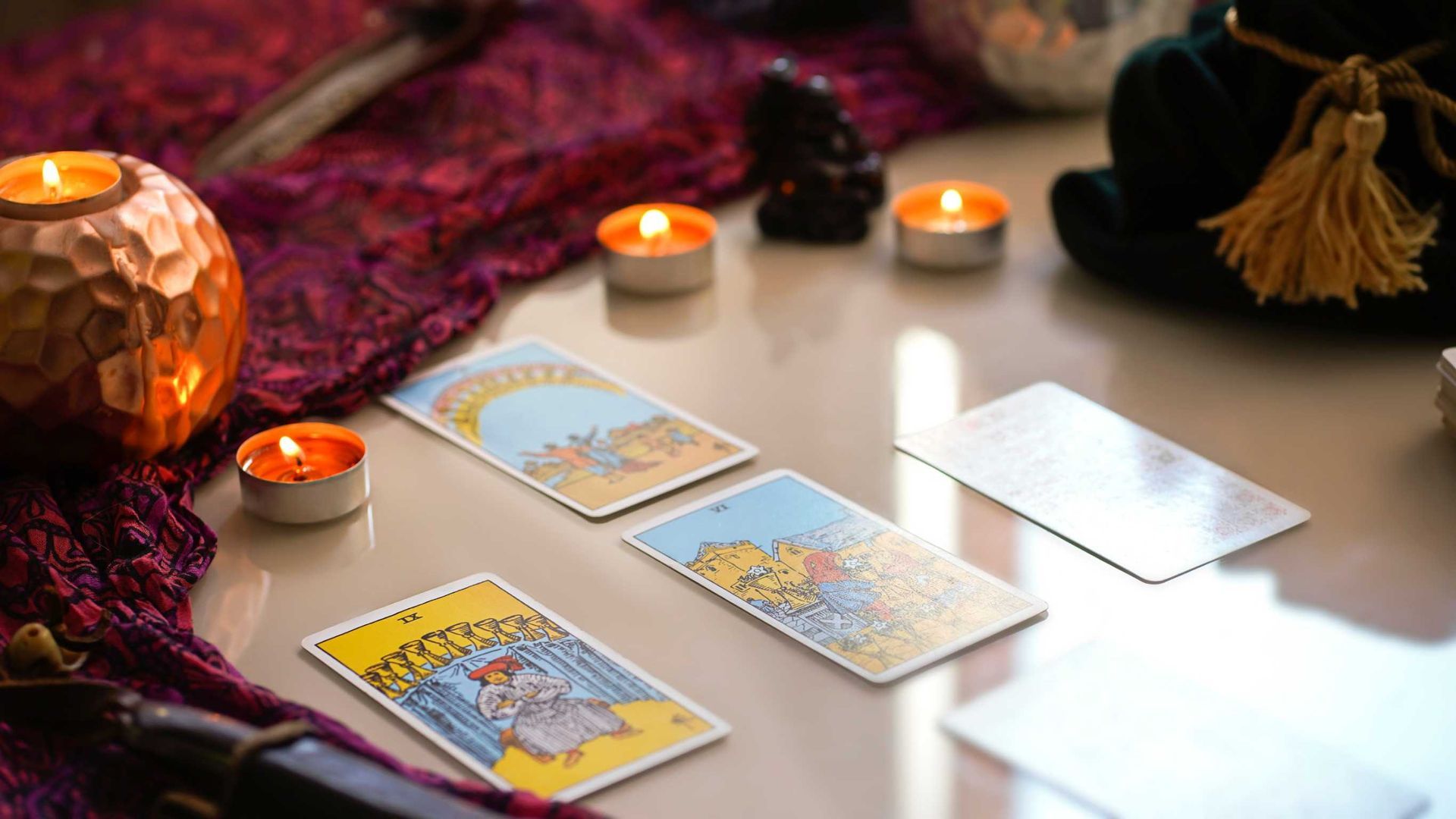 Una mesa cubierta con cartas de tarot y velas.