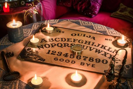 Una tabla ouija con velas está sobre una mesa.