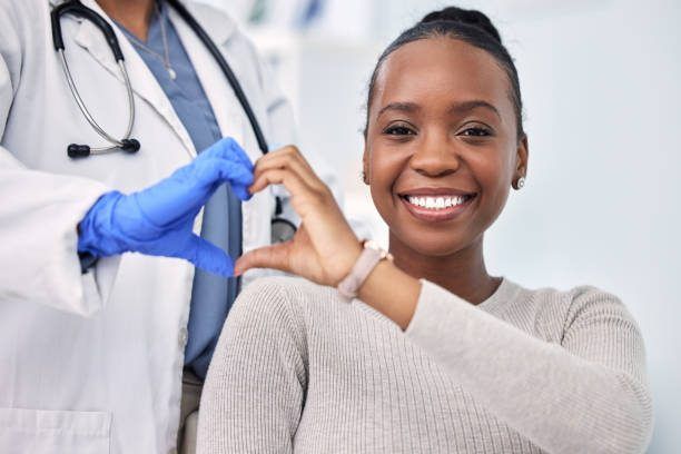 Un médico y un paciente están haciendo una figura de corazón con sus manos.