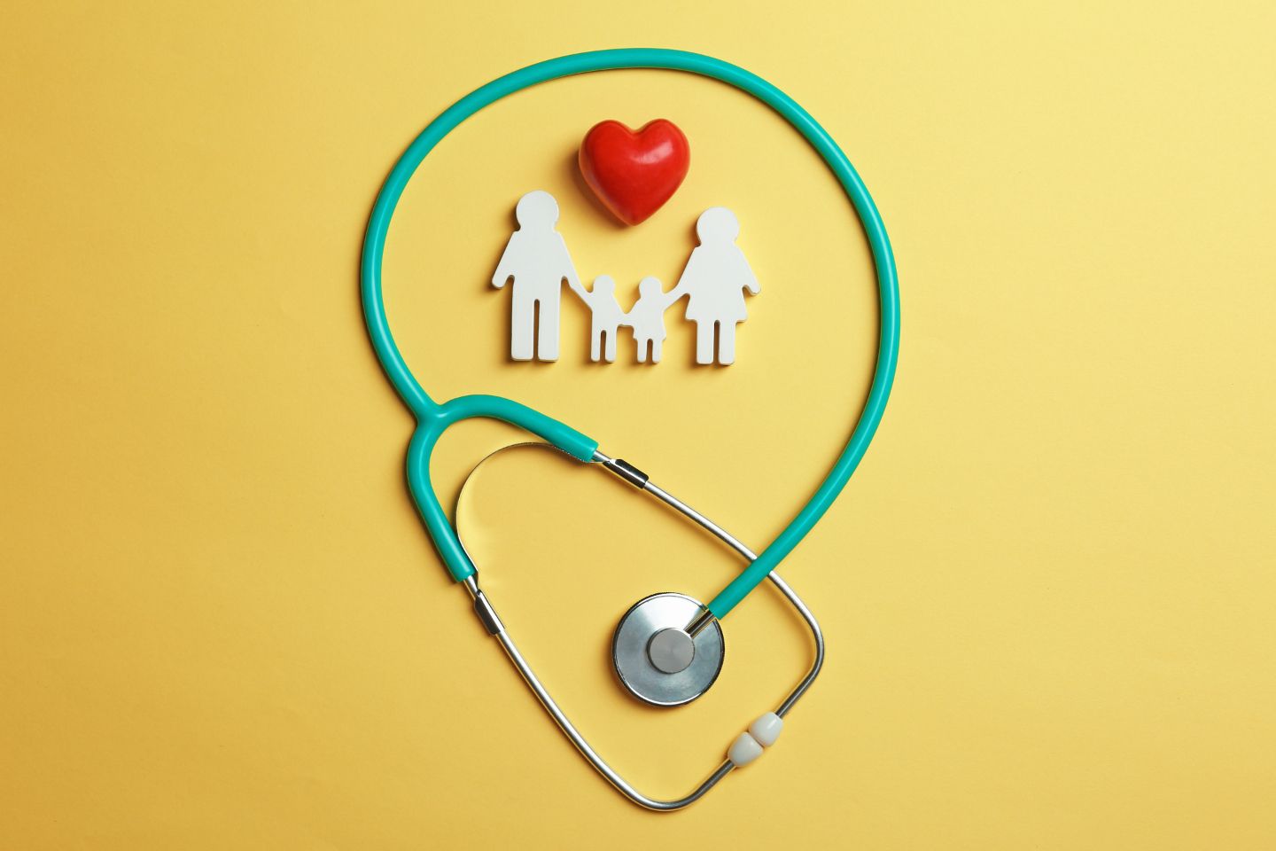 Un estetoscopio con un corazón y una familia recortados sobre un fondo amarillo.