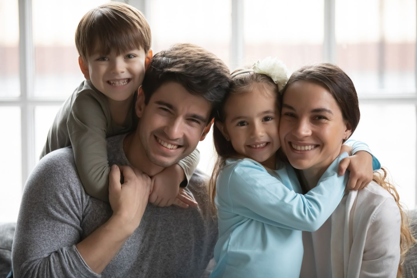 Una familia posa para una foto juntos frente a una ventana.