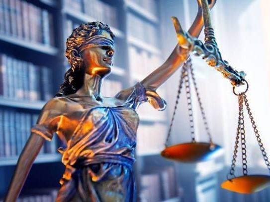 Una estatua de la Dama de la Justicia sosteniendo una balanza de la justicia en una biblioteca.