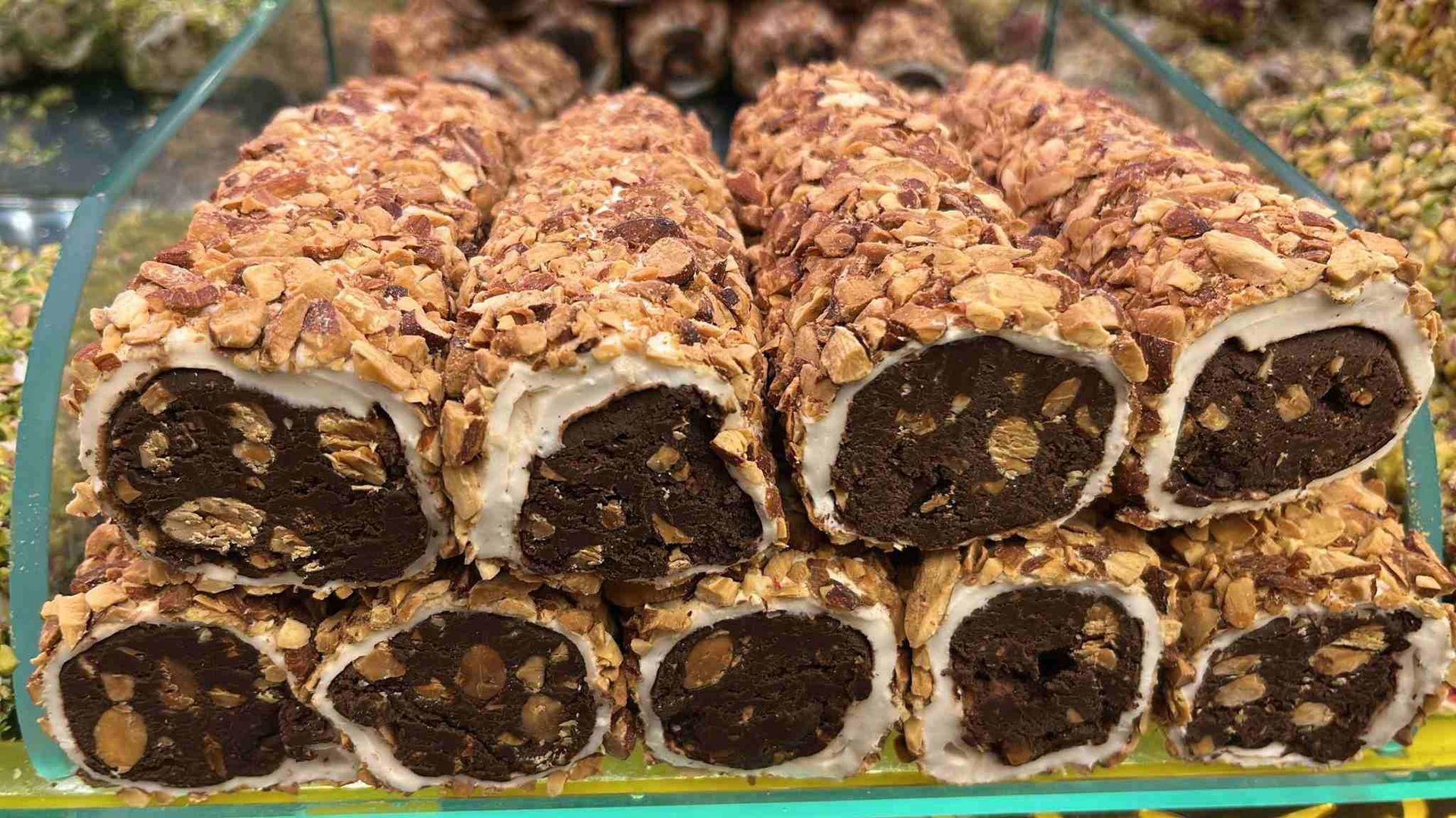 Troncos de postre de chocolate y nueces apilados en una bandeja, cortados para mostrar el relleno oscuro y la cobertura.