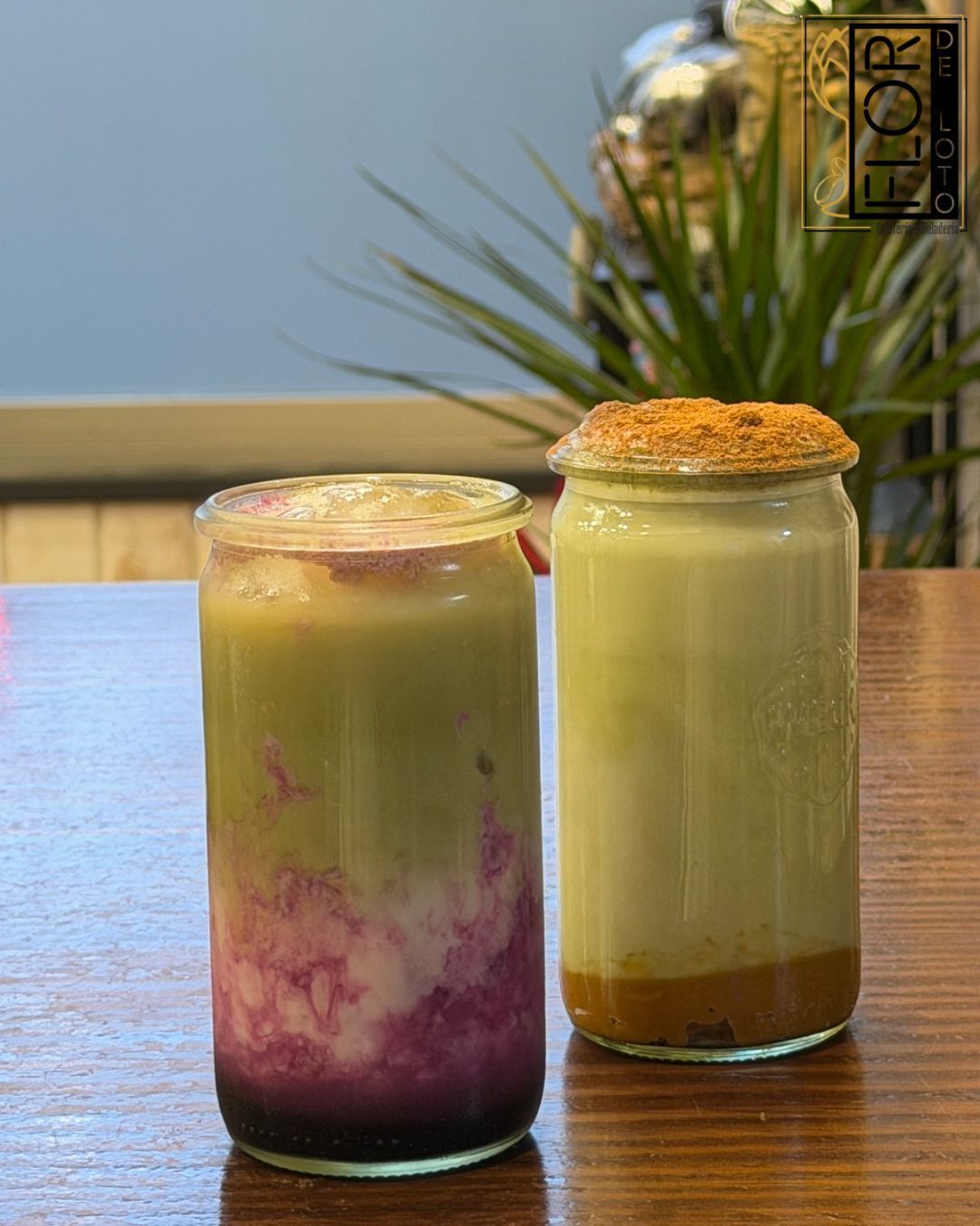 Dos bebidas heladas en tarros sobre una mesa, una morada y blanca, la otra verde pálido con una capa de espuma.