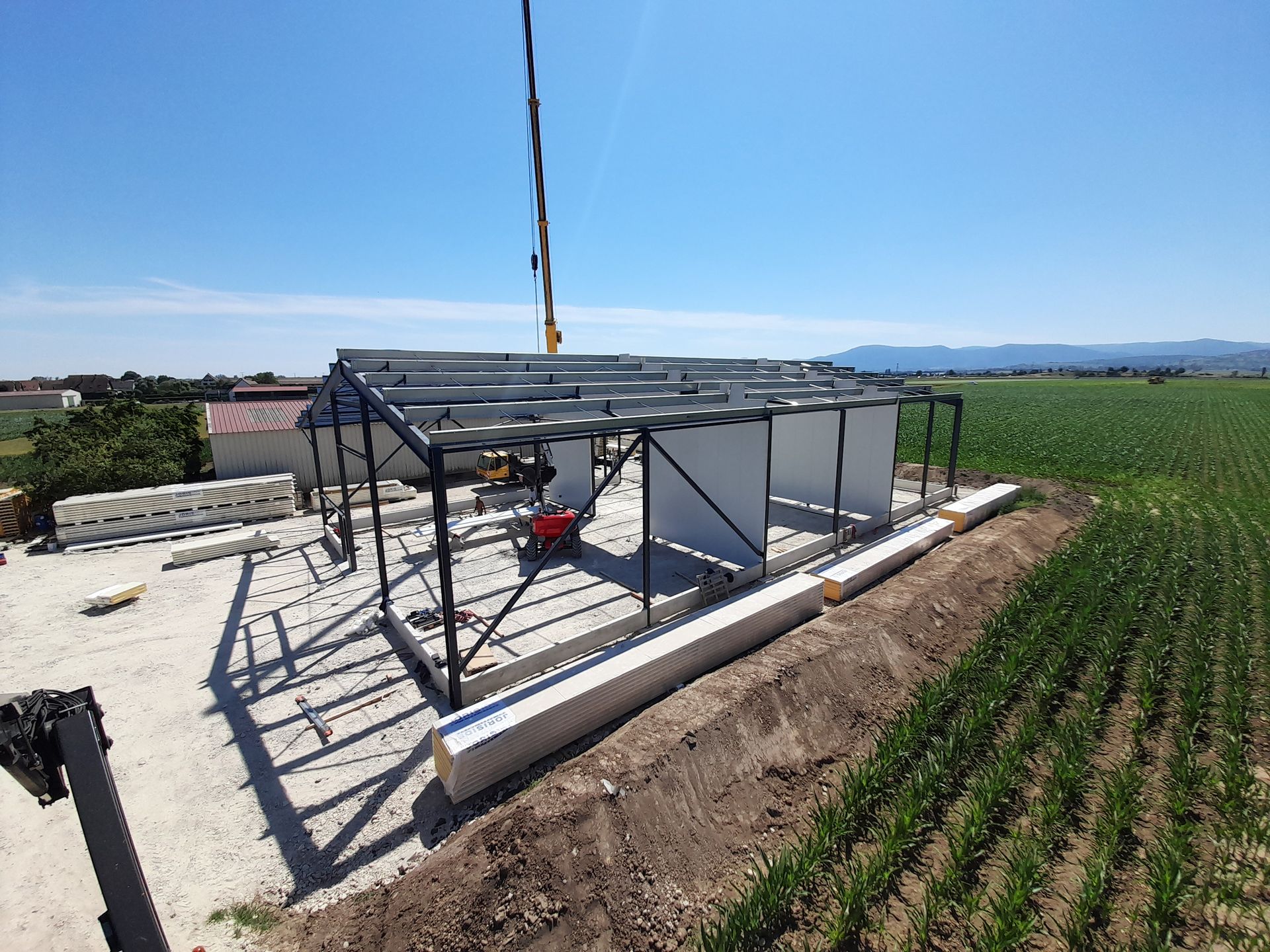 Petite structure métallique à ossature en construction au bord d’un champ verdoyant, par une journée ensoleillée