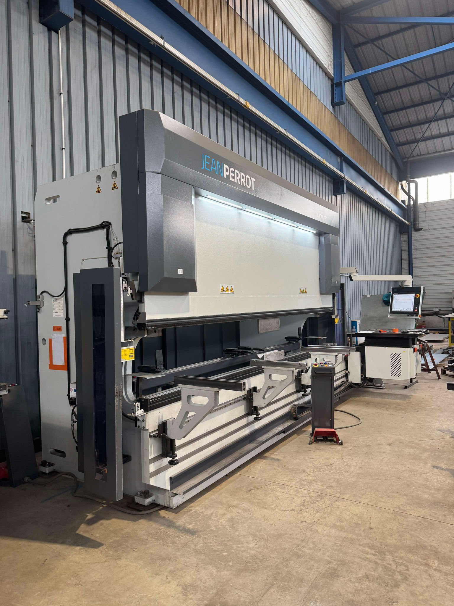 Grande machine CNC industrielle dans un entrepôt, avec des panneaux gris et une table de travail à l’avant.