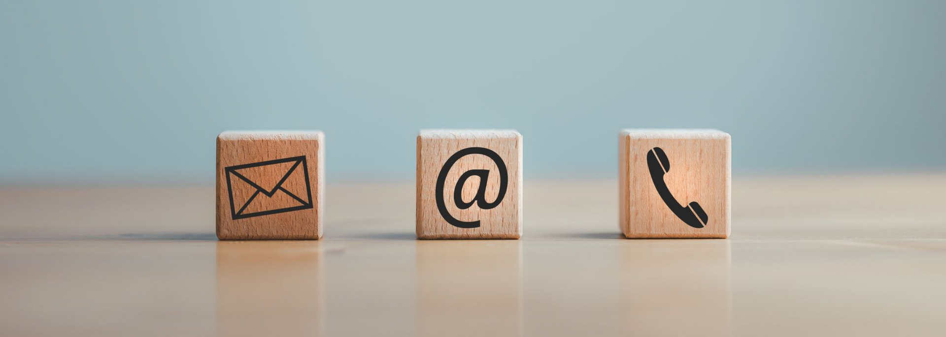 Trois blocs de bois clair alignés sur un bureau, chacun orné d'une icône.