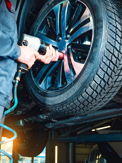 Un mécanicien utilise une clé à chocs pneumatique pour serrer les écrous de roue d'une voiture.