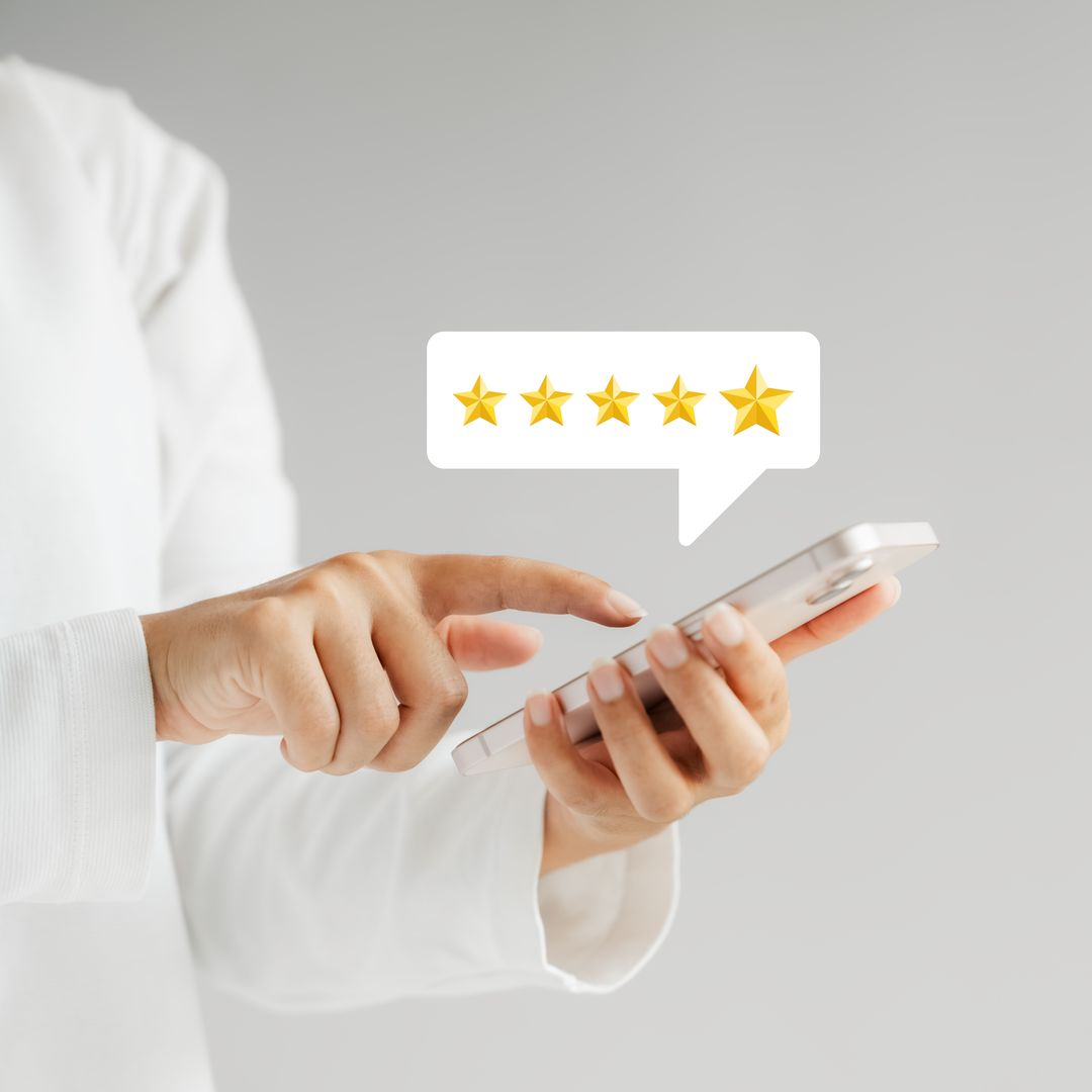 Une personne utilise un smartphone, affichant une icône de note cinq étoiles dans une bulle de dialogue.