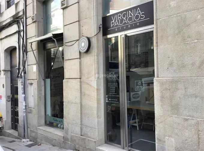 Exterior del Estudio Virginia Palacios, un negocio con puerta de cristal y letrero. El edificio es de piedra.