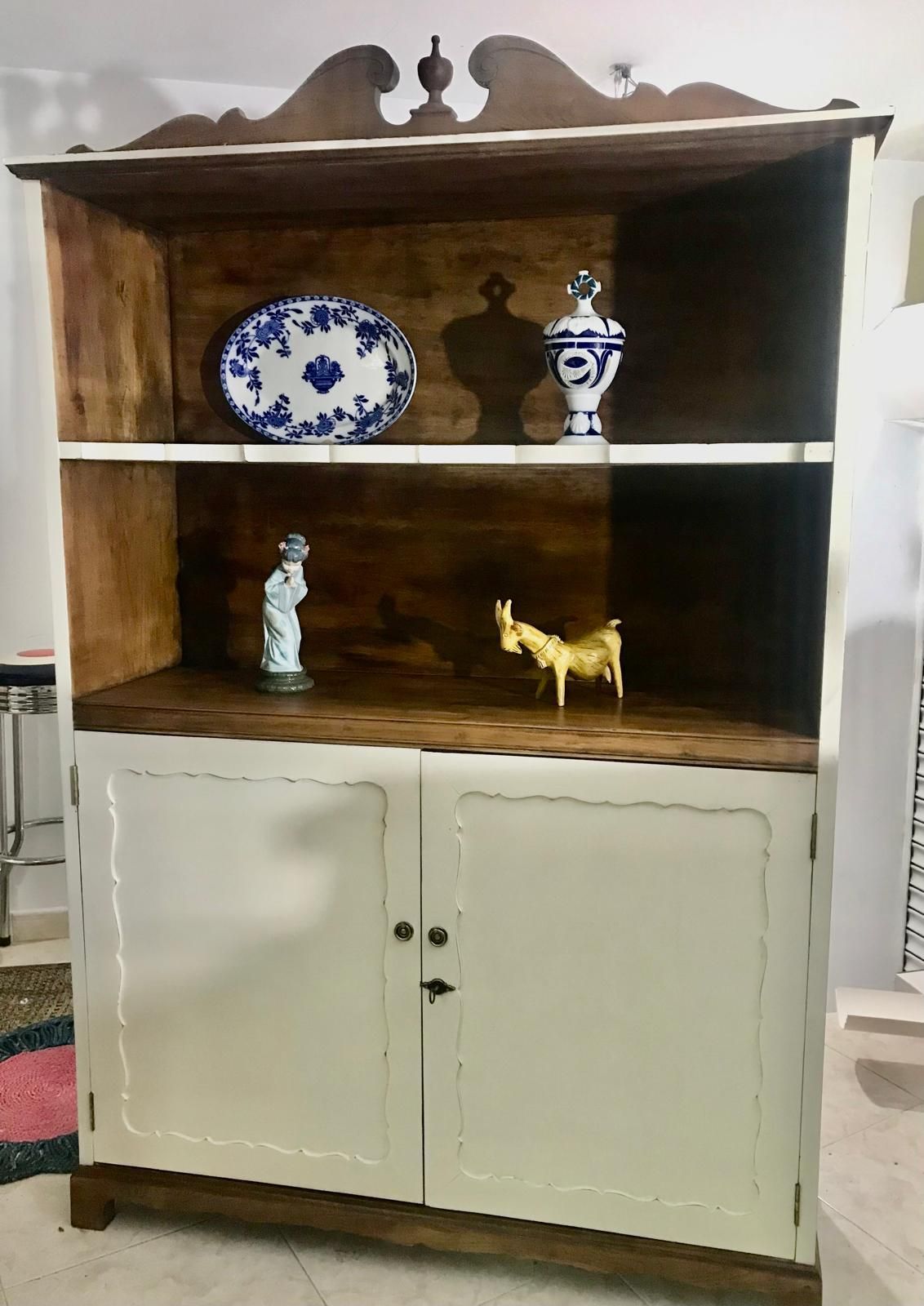 Armario de madera blanco y marrón con estantes, que contiene cerámica decorativa azul y blanca y figuras.