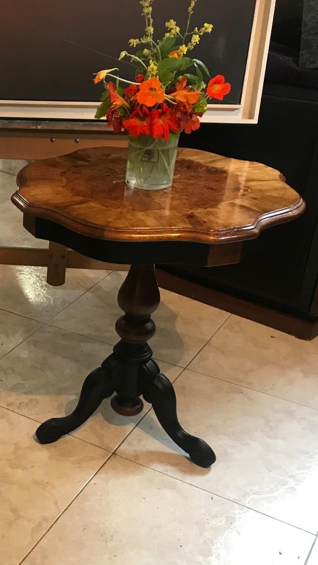 Una pequeña mesa auxiliar de madera con flores en un jarrón encima, en una habitación.