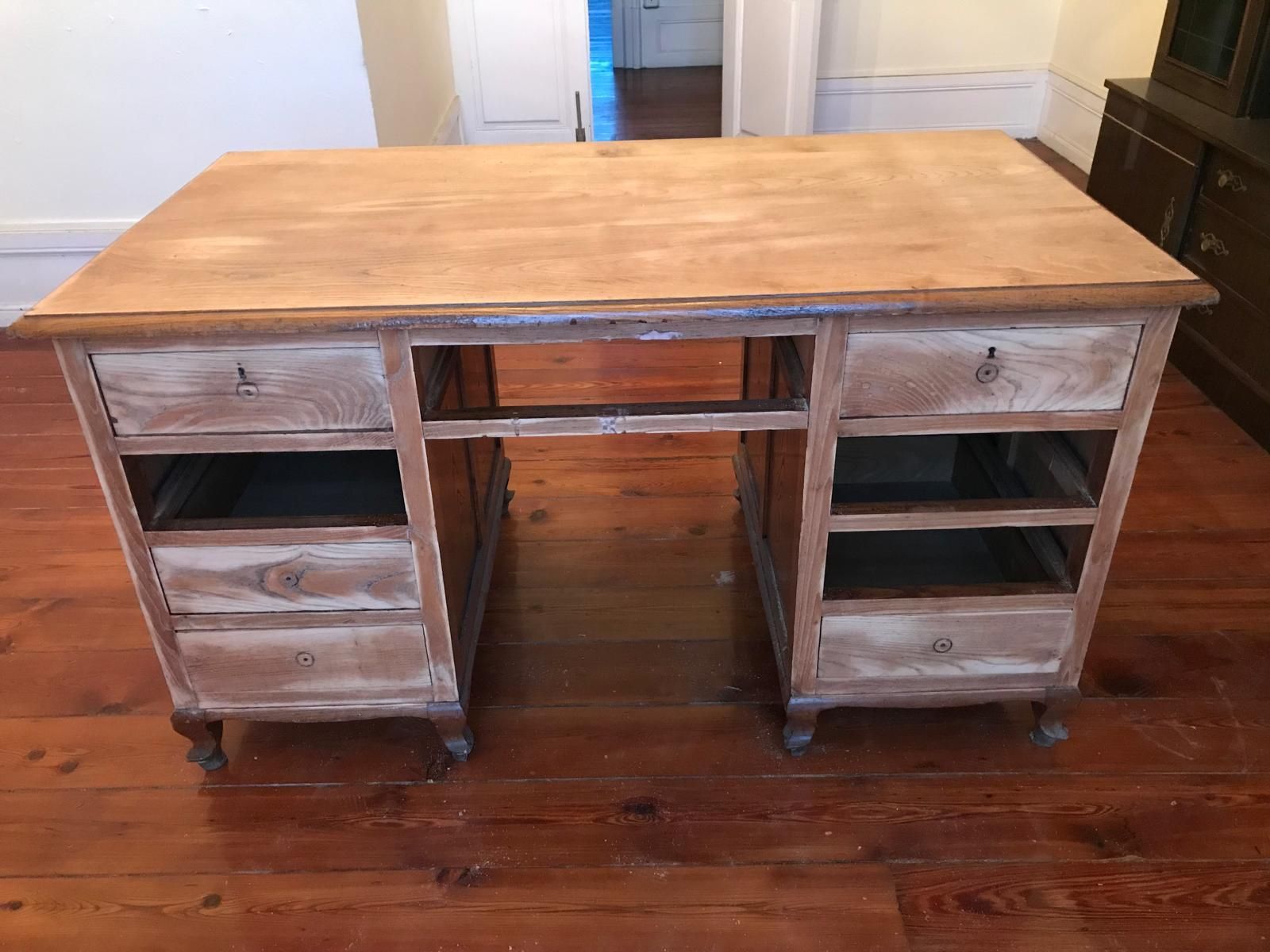 Escritorio de madera con cajones faltantes, colocado sobre un piso de madera.