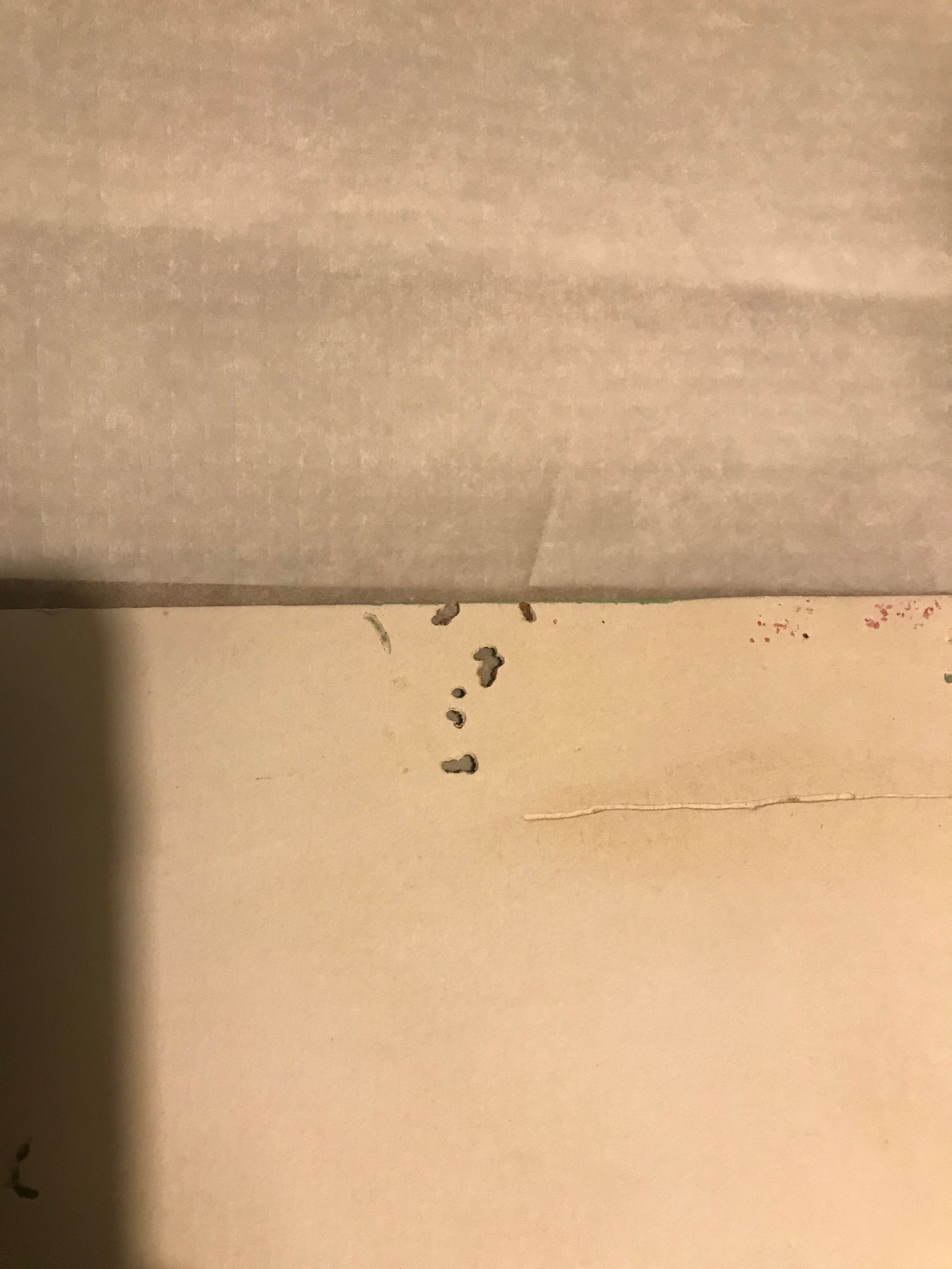 Pared beige con pequeñas manchas oscuras cerca de la parte inferior; una sección más clara arriba.