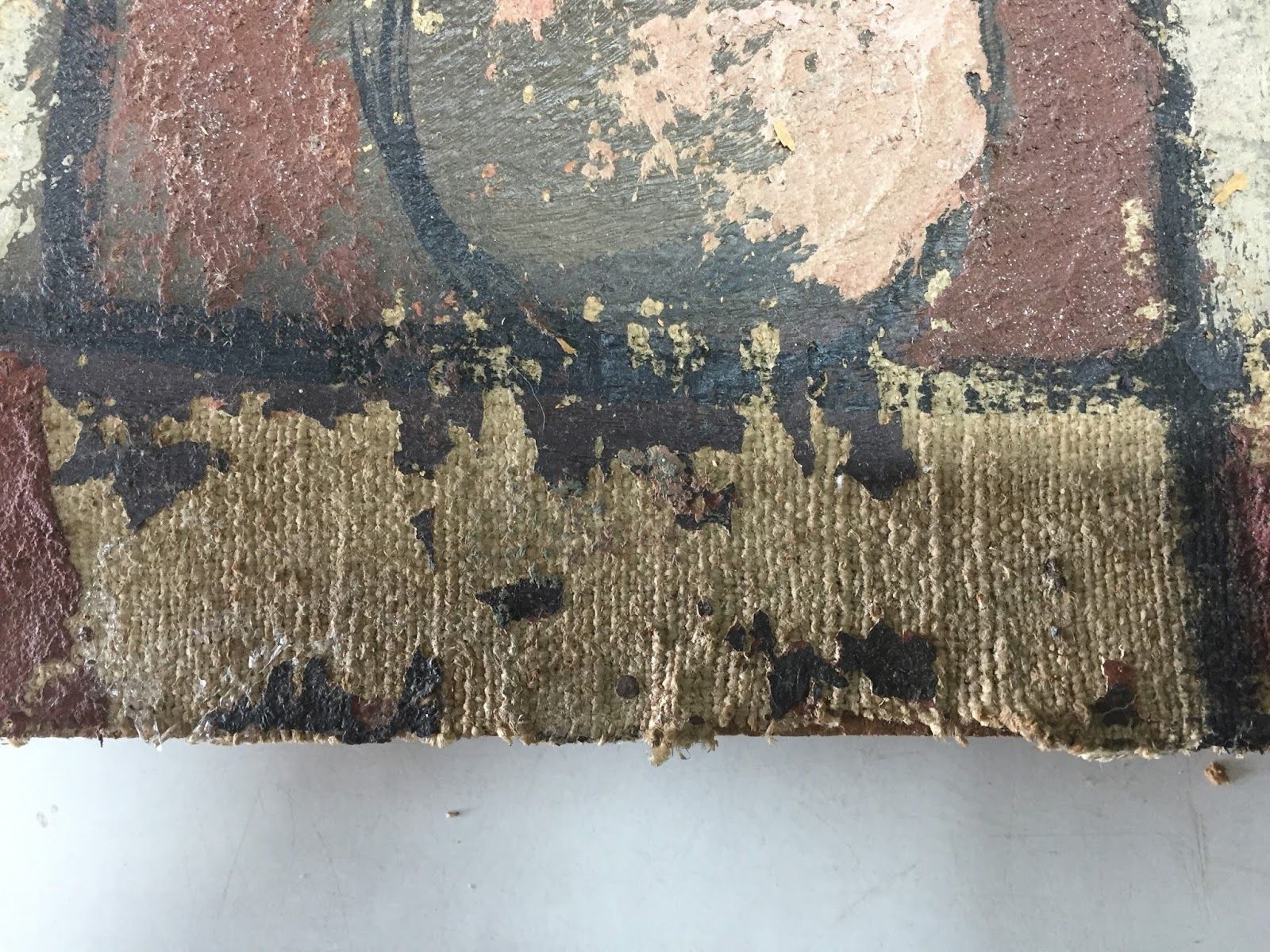 Primer plano de una obra de arte envejecida y descascarada con tonos dorados, marrones y rojos.