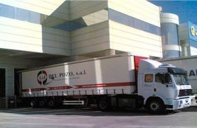 Un camión semirremolque blanco está estacionado frente a un edificio.