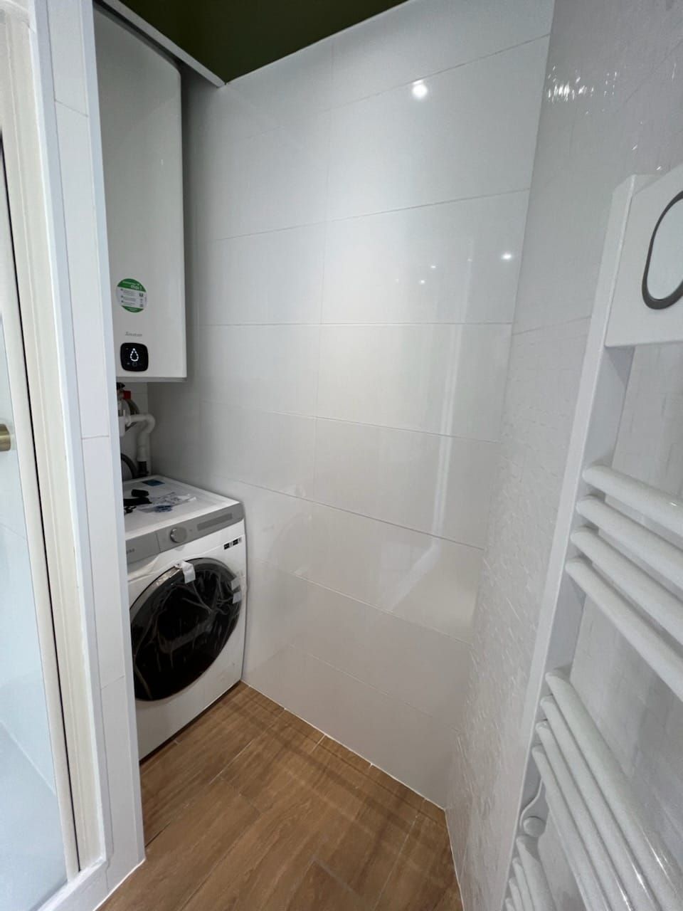 Machine à laver sous un ballon d'eau chaude face à un sèche-serviettes